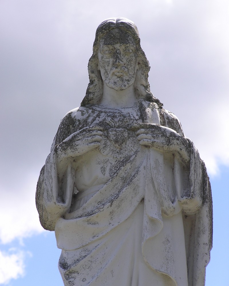 A statue of jesus is shown in front of the sky.