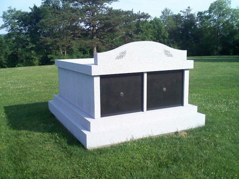 A white grave with two black doors in the middle.