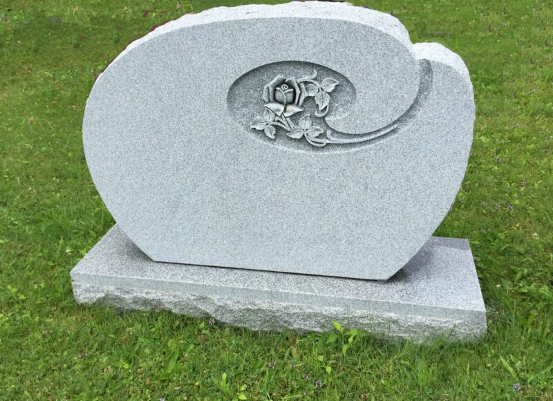 A gray stone grave marker with a flower design.