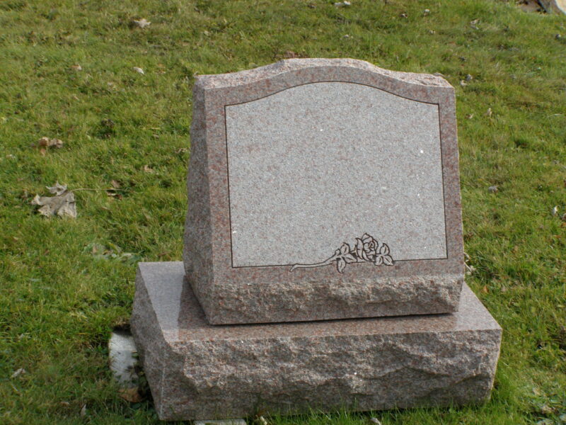 A stone grave marker sitting in the grass.