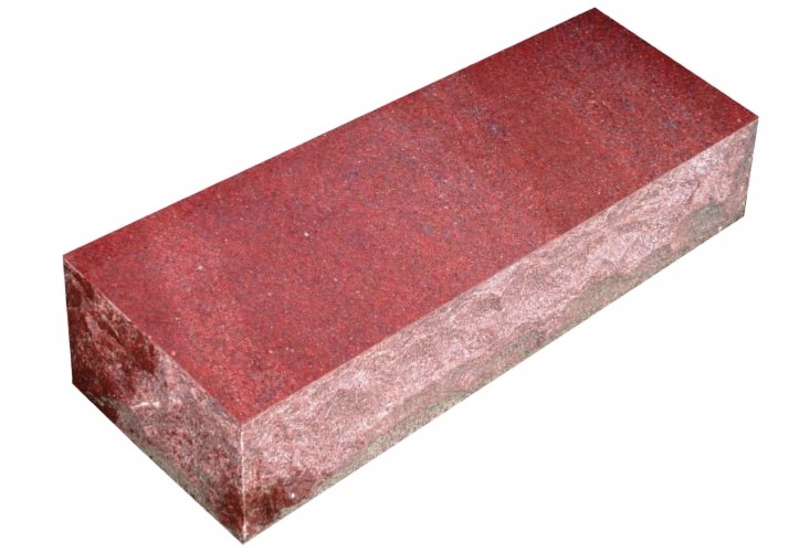 A red brick is sitting on the ground.