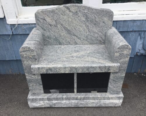 A marble chair with two black seats.