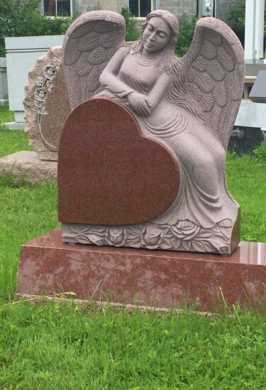 A stone statue of an angel sitting on top of a heart.