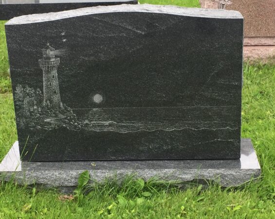 A black granite headstone with a lighthouse on it.
